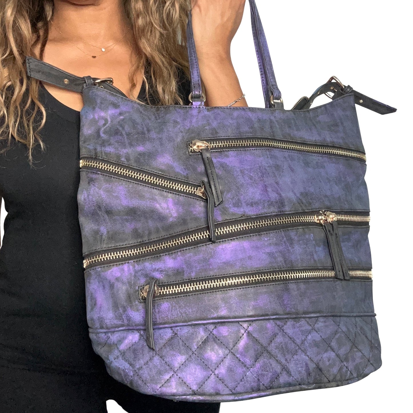 Purple handbag with gold zippers held by a person