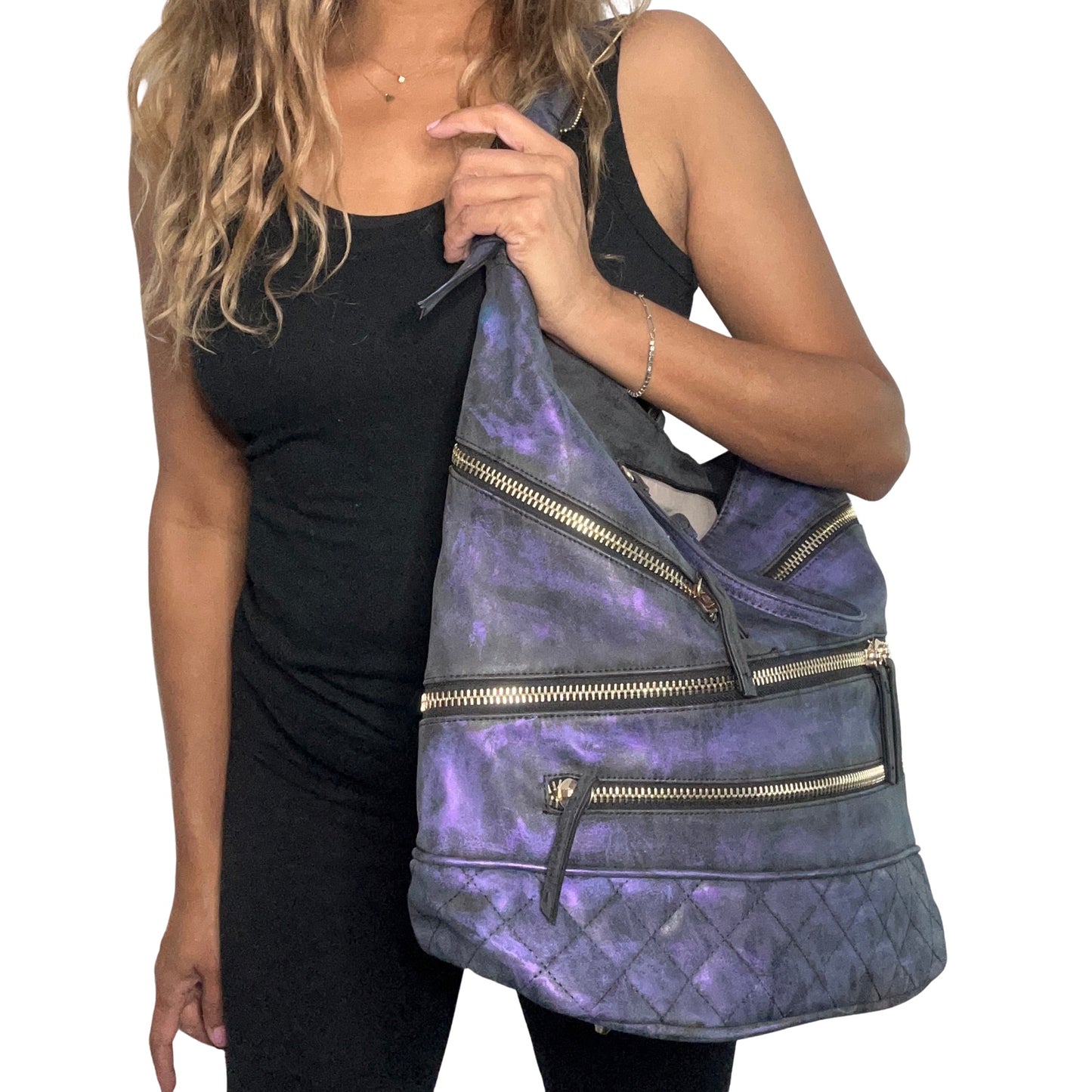Person holding a blue and purple quilted bag with gold zippers on a white background