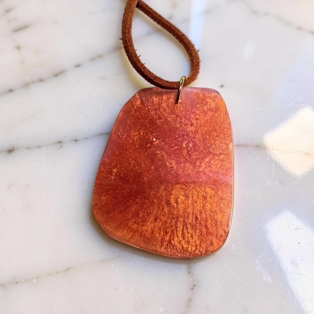 Brown leather cord with pendant on a marble surface