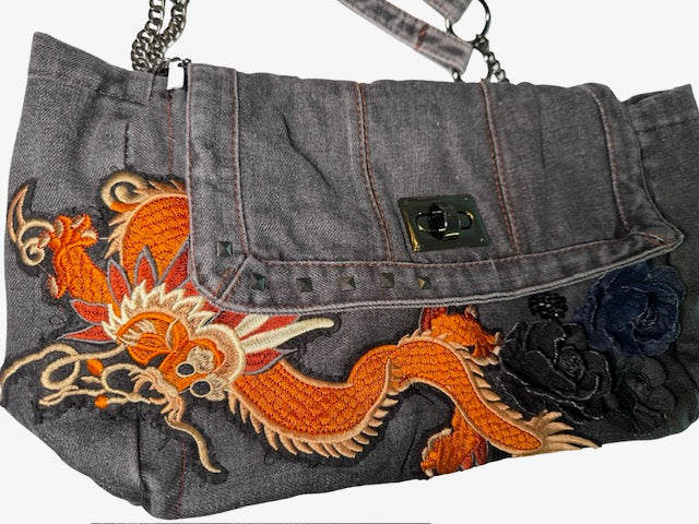 Denim handbag with embroidered dragon design on a white background