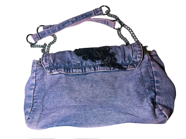 Denim handbag with black floral embellishments and chain strap on a white background