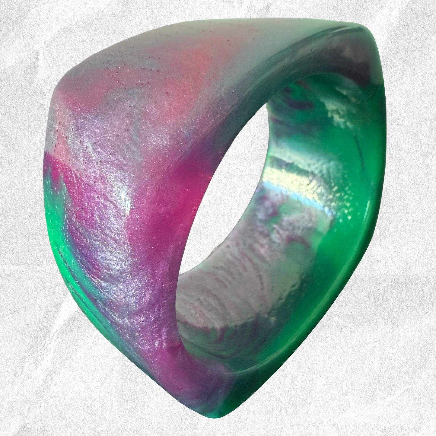 Colorful bracelet with a gradient of pink, purple, and green on a light gray background