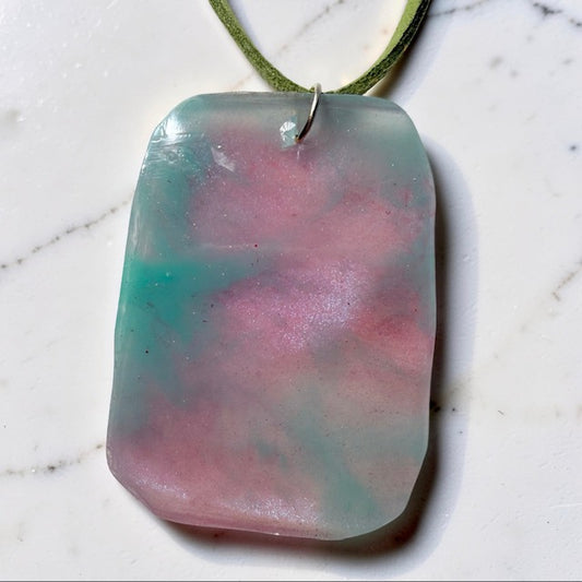 Rectangular pendant with pink and green marbled pattern on a white marble surface