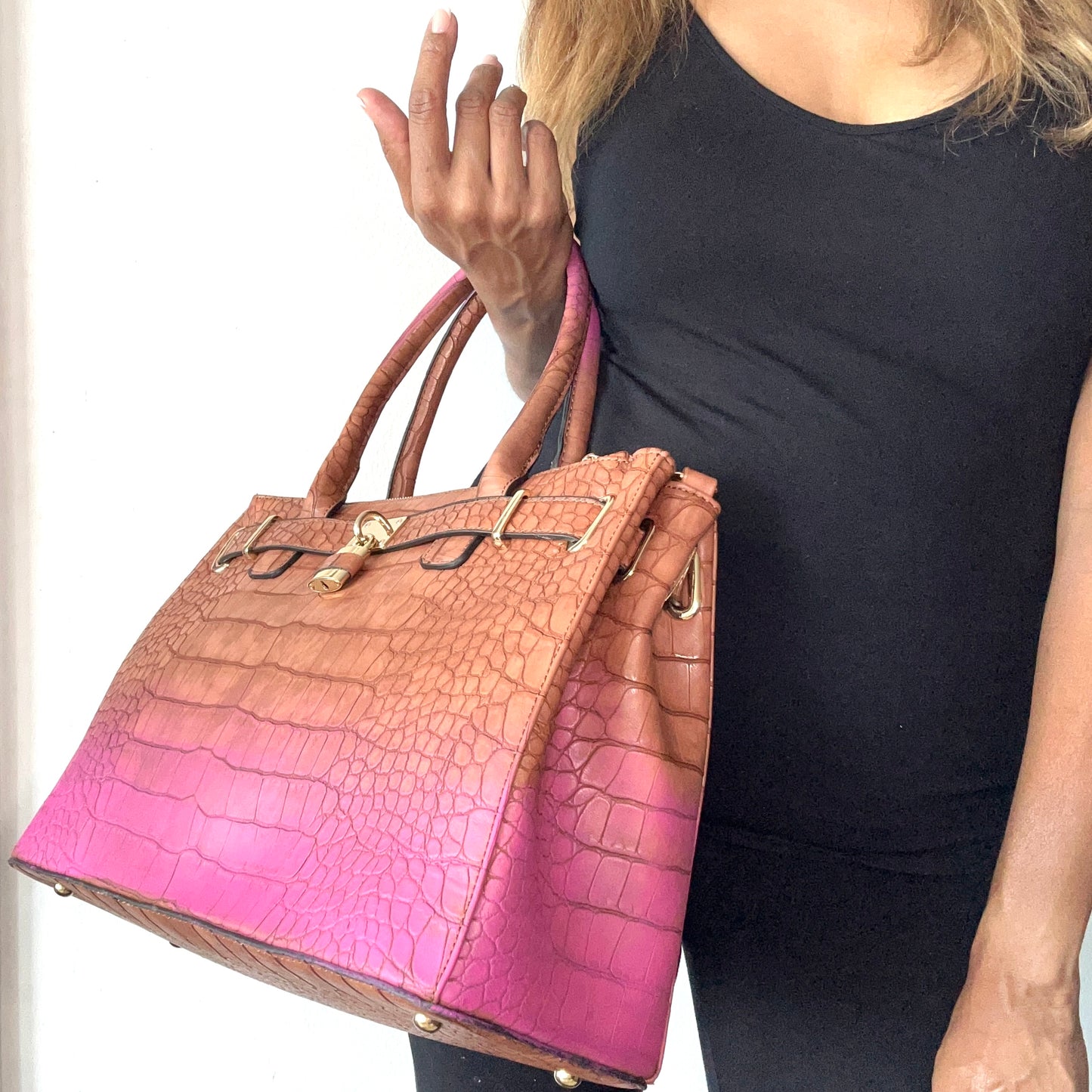 Person holding a gradient handbag transitioning from pink to brown.