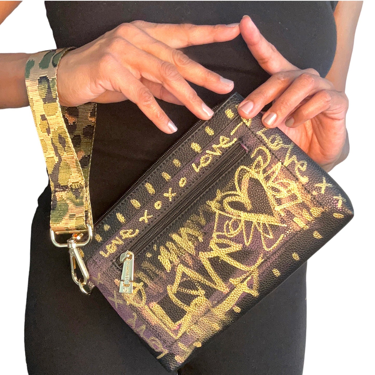 Hand holding a brown clutch with gold designs and a matching strap.