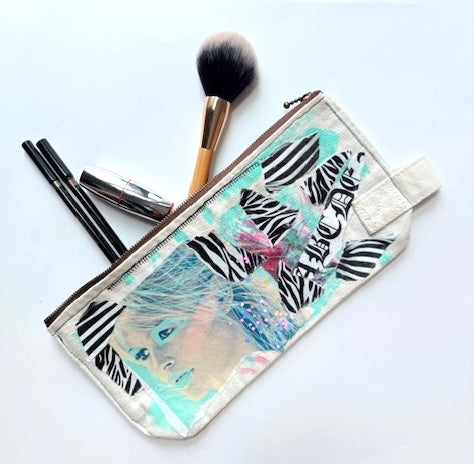 Makeup pouch with zebra pattern and makeup brushes on a white background
