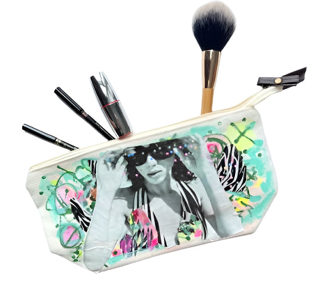 Makeup pouch with artistic design, makeup brushes, and lip products on a light blue background