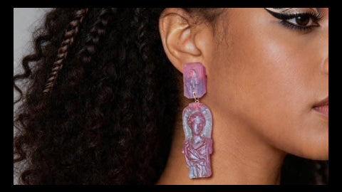 Close-up of a woman wearing colorful earrings with a neutral background