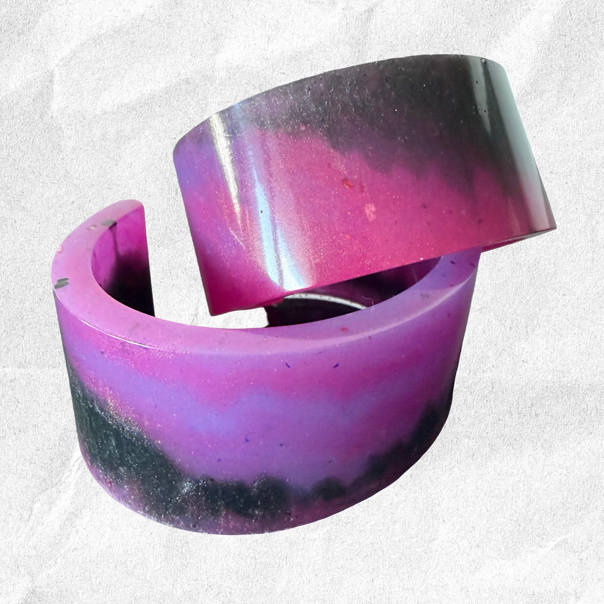 Purple and black resin ring on a textured white background