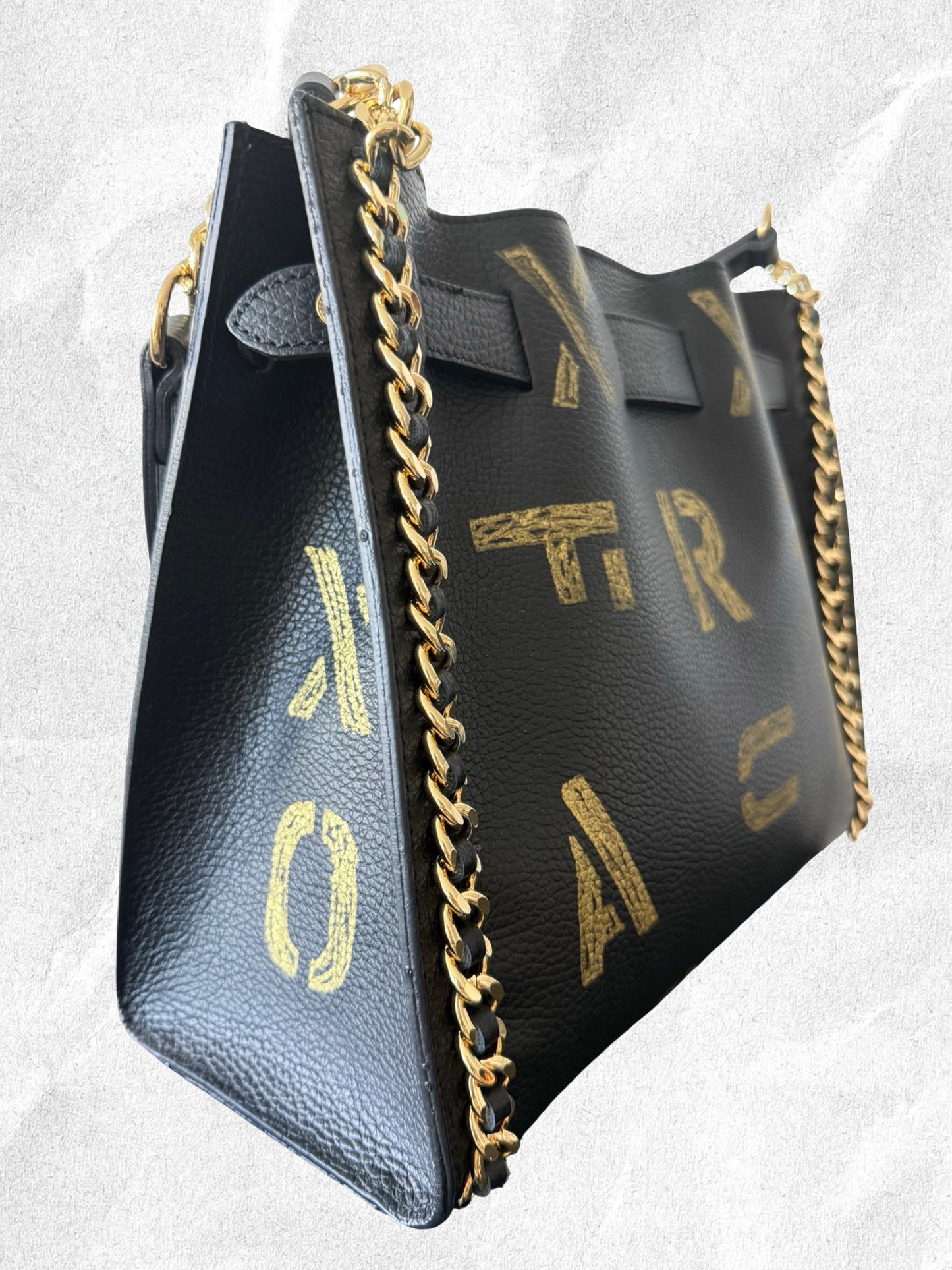Myxt art black leather handbag with gold chain strap on a light gray background