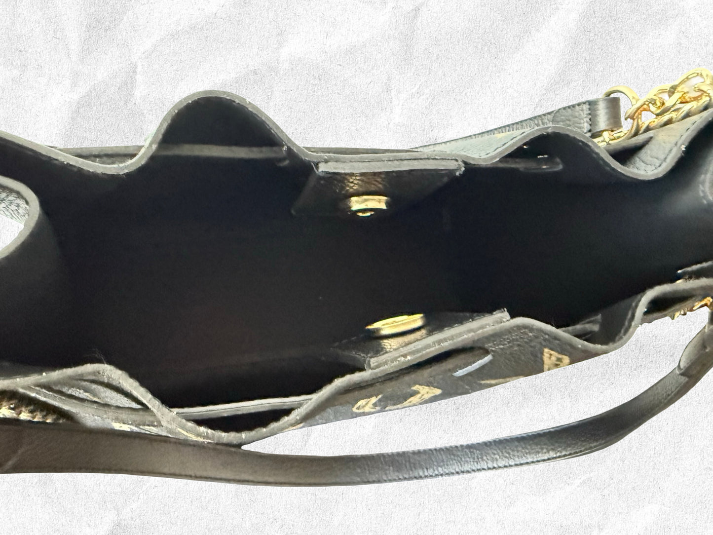 Close-up of a black handbag with gold accents on a white background