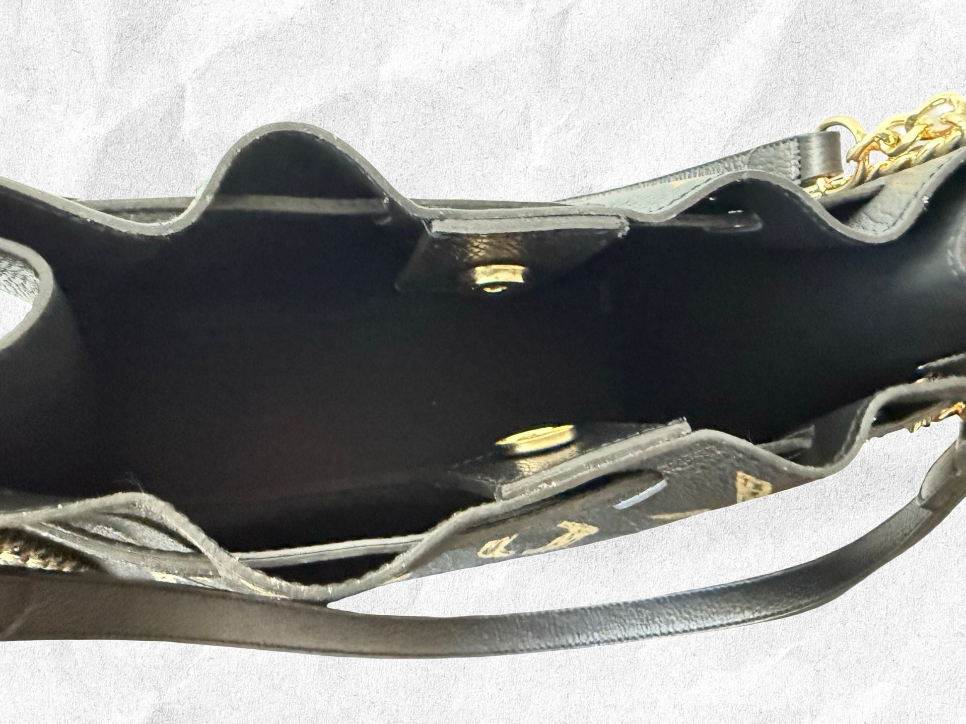 Close-up of a black handbag with gold accents on a white background