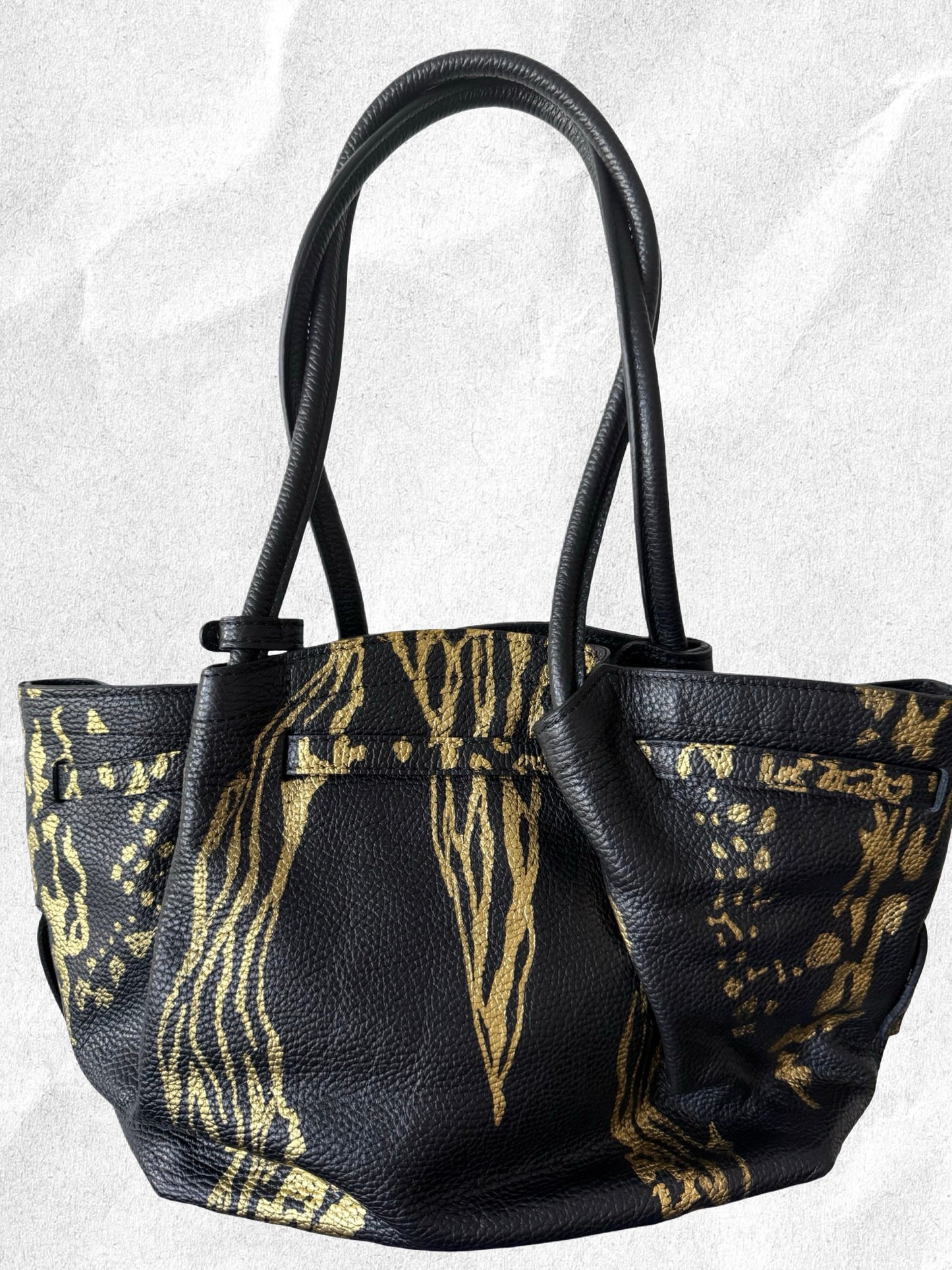 Black handbag with gold patterns on a light gray background