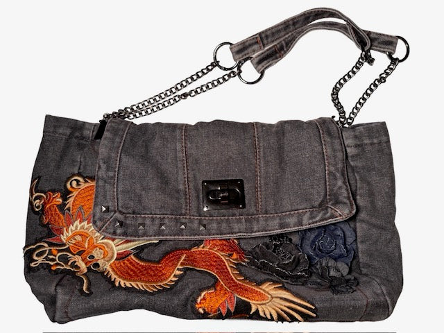 Denim handbag with dragon embroidery and chain strap on a white background