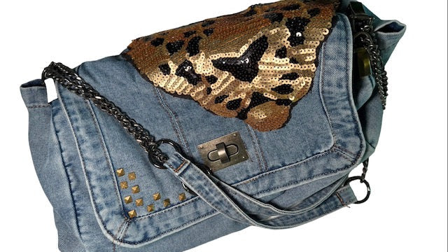 Denim handbag with gold sequin butterfly and studded details on a white background