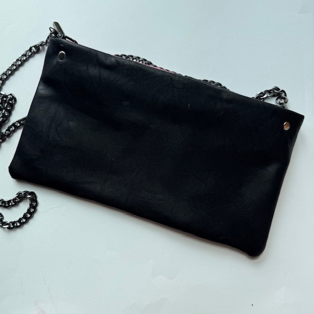 Black leather clutch bag with chain strap on a light gray background