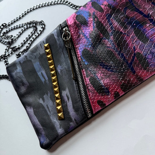 Multicolored patterned clutch with gold studded detail on a white background