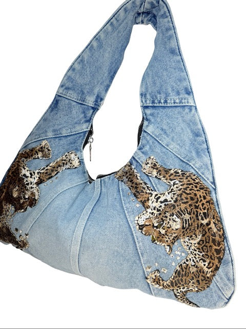 Denim handbag with leopard print designs on a white background