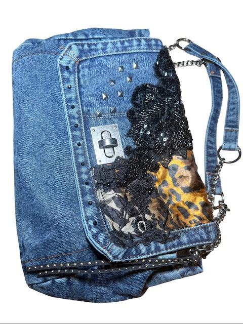 Denim handbag with black lace and leopard print accents on a white background