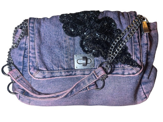 Denim handbag with black floral embellishment and chain strap on a white background