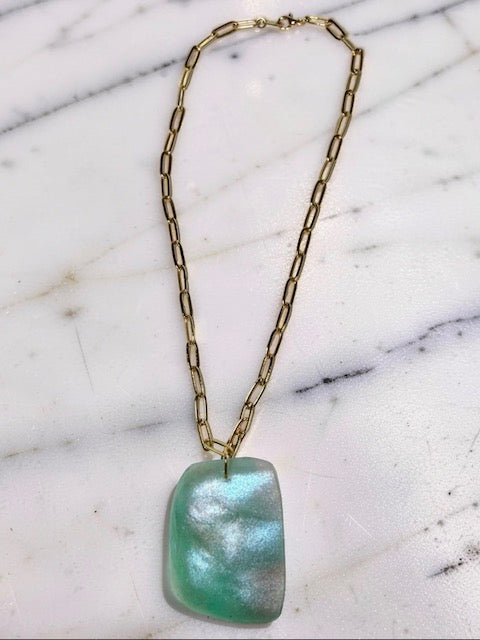 Necklace with an aqua-colored pendant on a marble surface