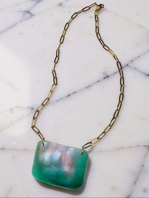 Necklace with a green pendant on a marble surface