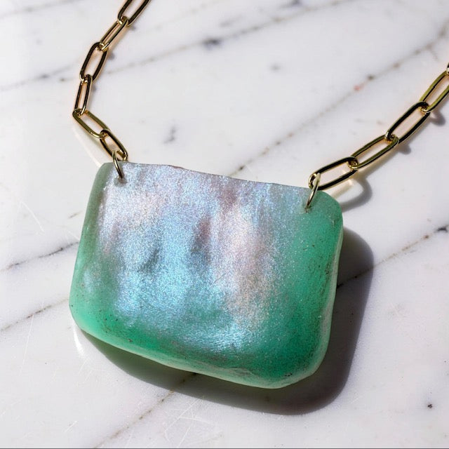 Necklace with an aqua-colored pendant on a marble surface