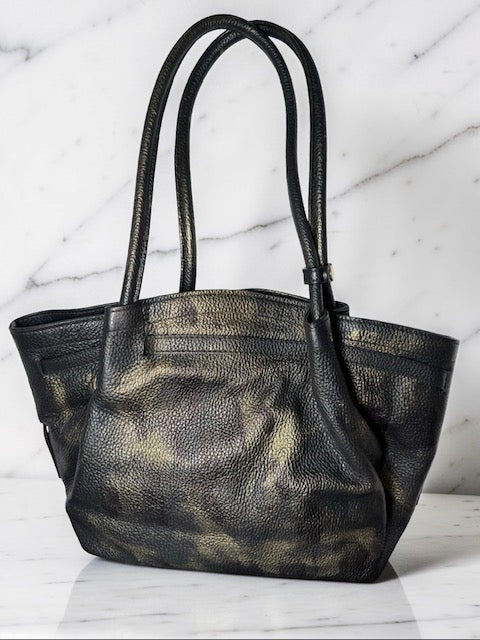 Black leather handbag with gold accents on a marble surface