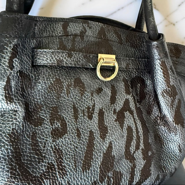 Leopard print handbag with a gold clasp on a neutral background