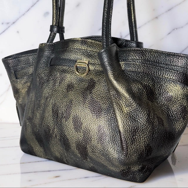 Black leather handbag with gold accents on a marble surface