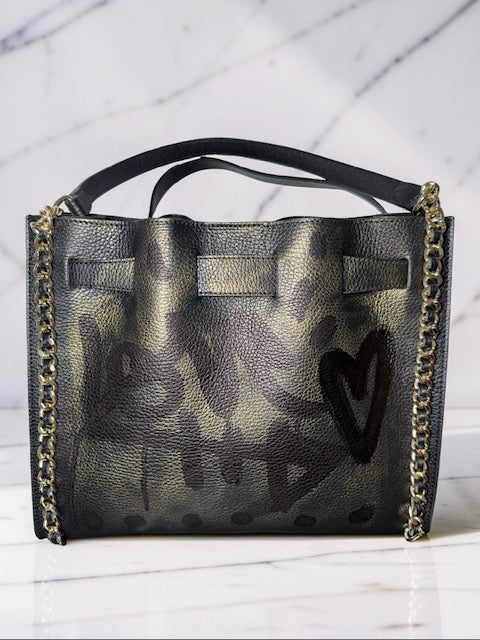 Black handbag with gold chain detail and heart design on a white background