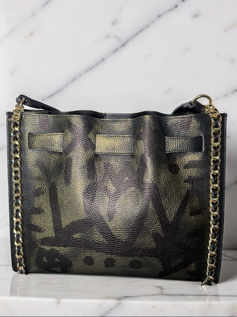 Black leather handbag with gold chain strap on a white marble surface