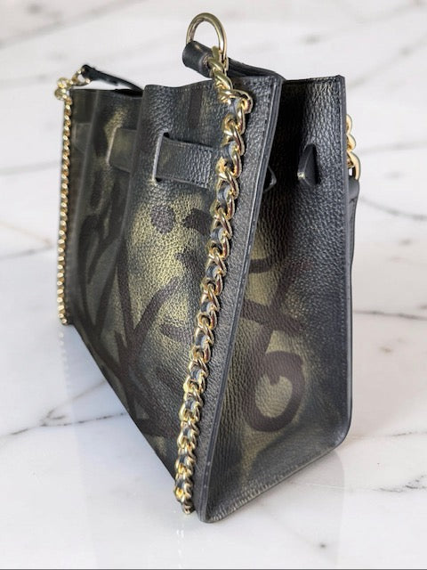 Black handbag with gold chain detail on a marble surface