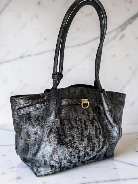 Black and gray leopard print handbag on a light wooden surface