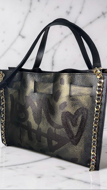 Black handbag with gold chain detail on a marble surface