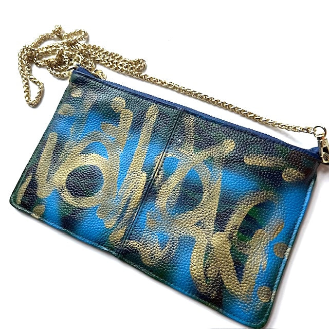 Blue and gold patterned clutch bag with a chain strap on a white background