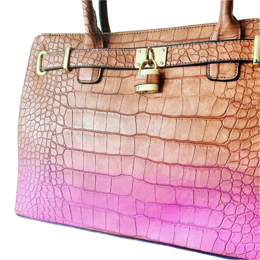Handbag with pink to brown gradient and gold hardware on a light blue background